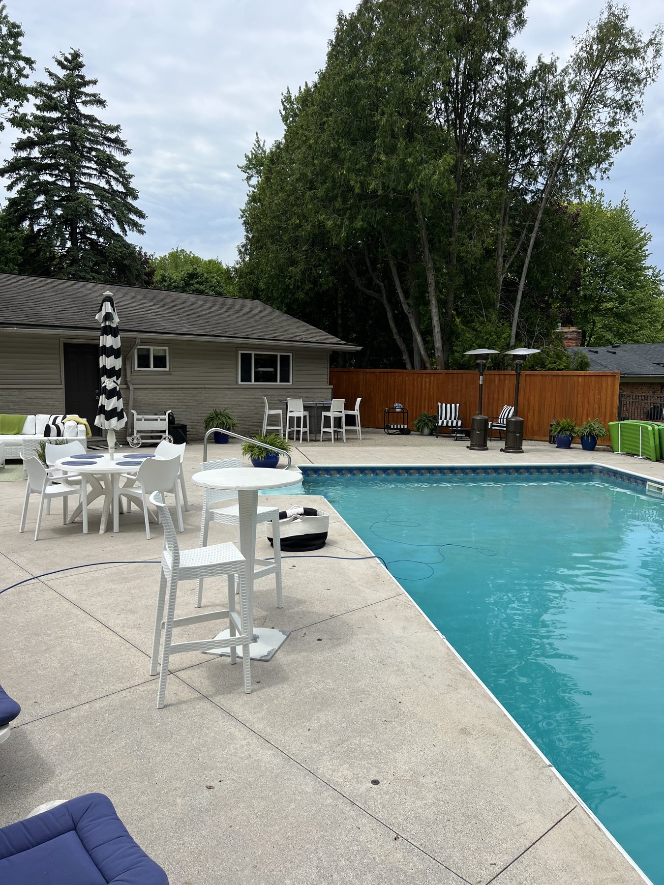Residential pool patio with seating, a fence, and trees