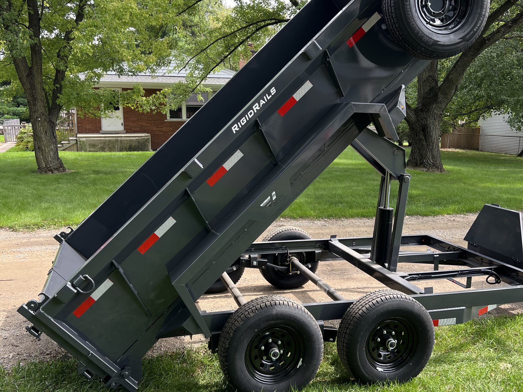 Dump trailer bed raised, unloading yard waste